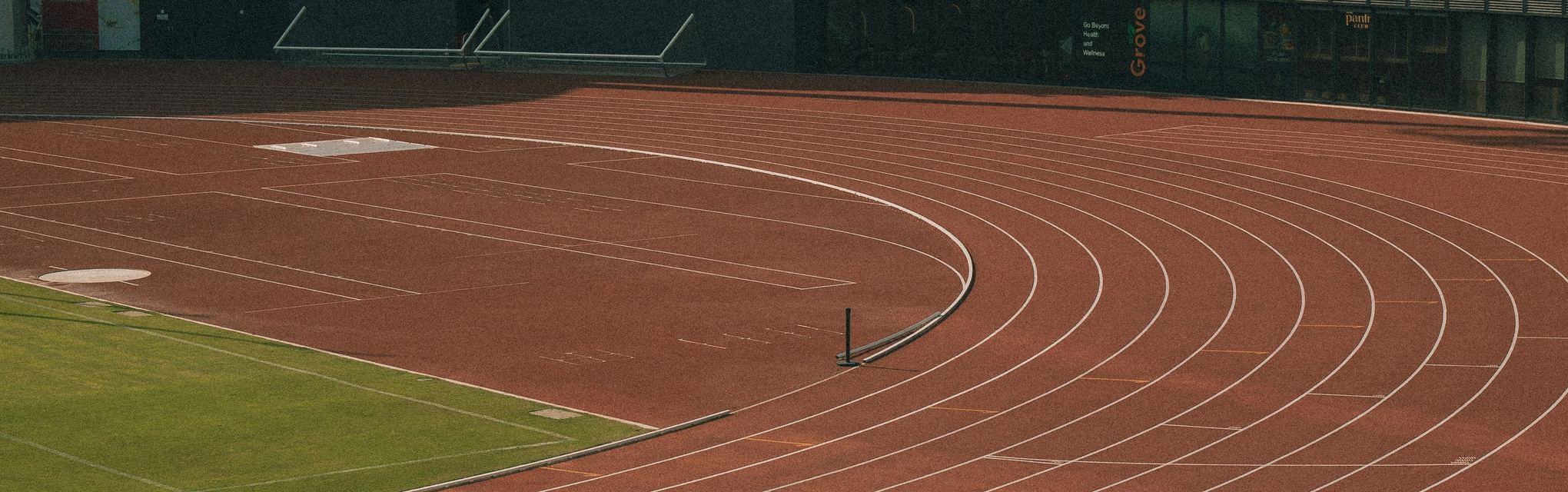 An empty athletics track beside a modern stadium building
